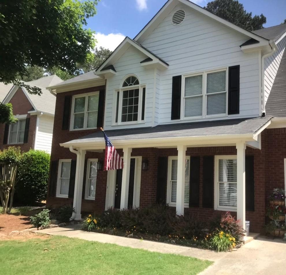 Two-storey home with repainted pale blue siding, white porch columns and dark shutters