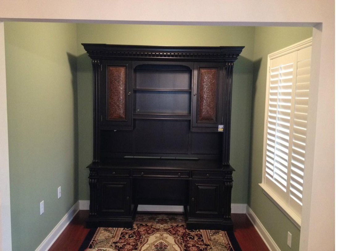 Home office alcove with sage green walls, white baseboards and a dark timber built-in desk