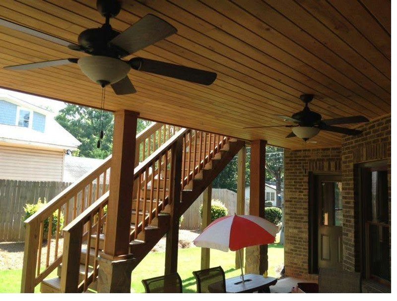 Covered porch beneath a deck with a stained tongue-and-groove timber ceiling and matching stair rails
